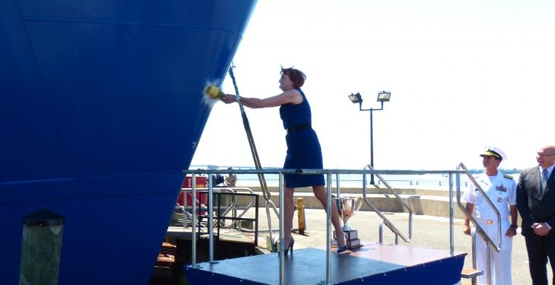 Photo of Jan Helis as she smashes a champagne bottle against the prow of the T/V Kings Pointer