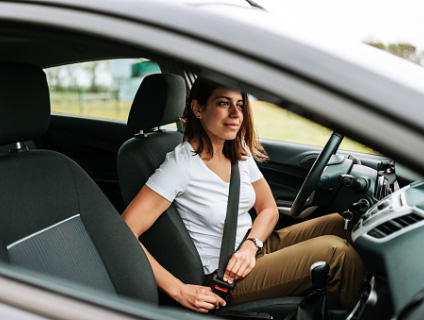 A woman buckles her seatbelt.