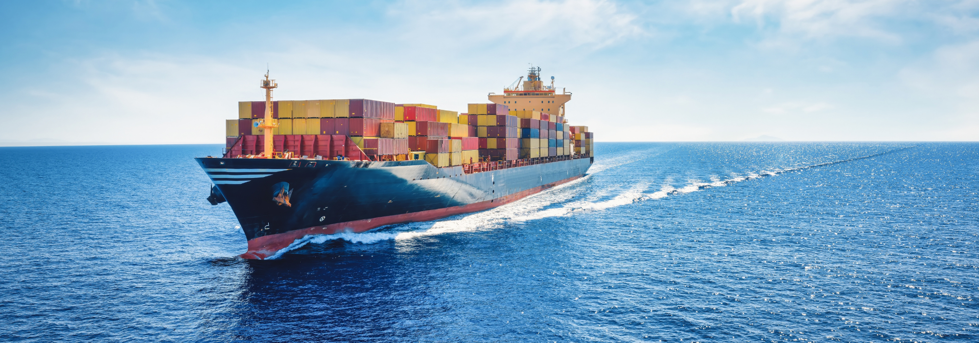 A cargo ship crossing the ocean, loaded with freight containers 