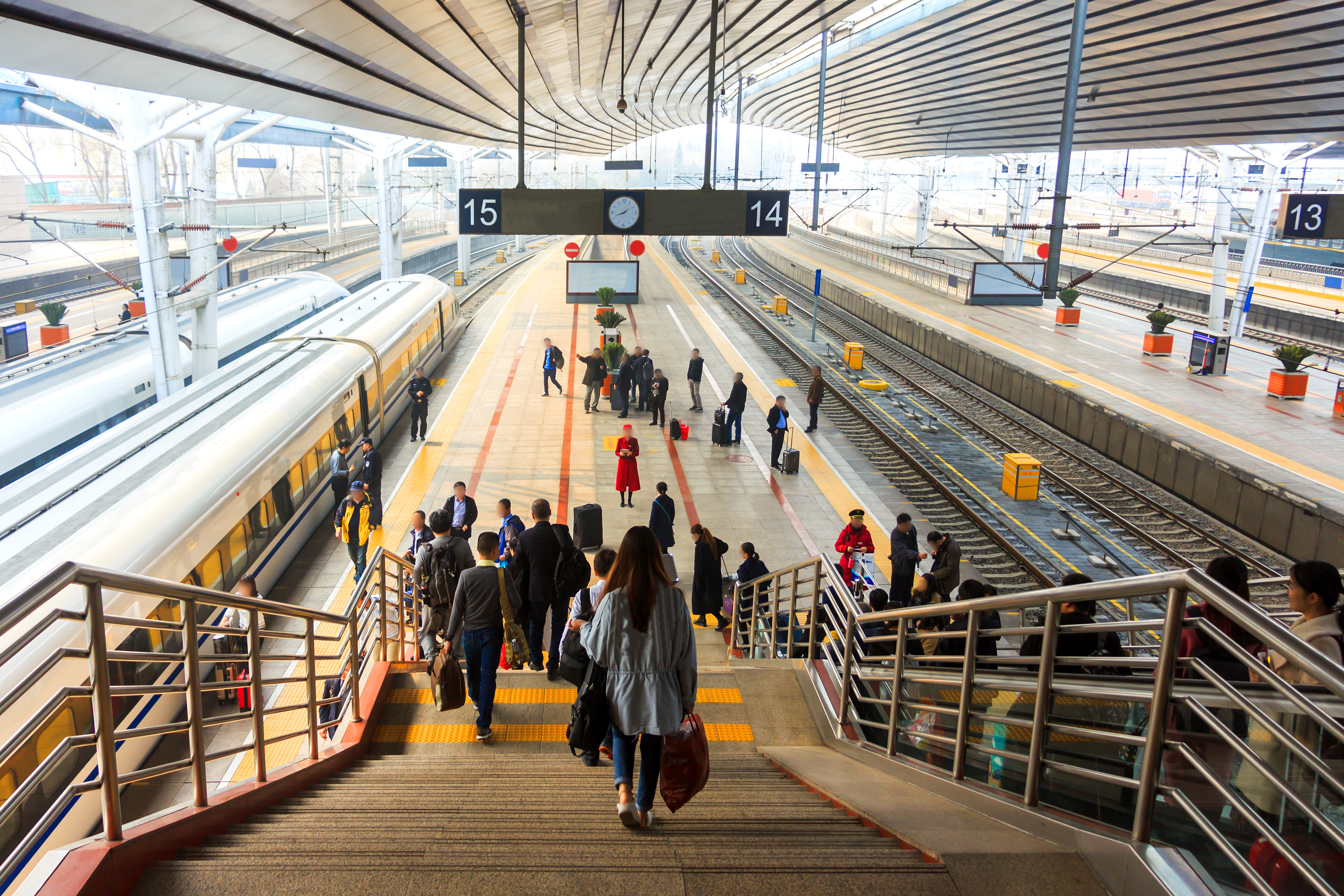 A busy train station platform and staircase.