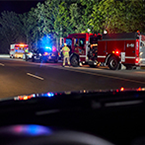 A fire truck and ambulance with EMS crews respond at the scene of a car crash.