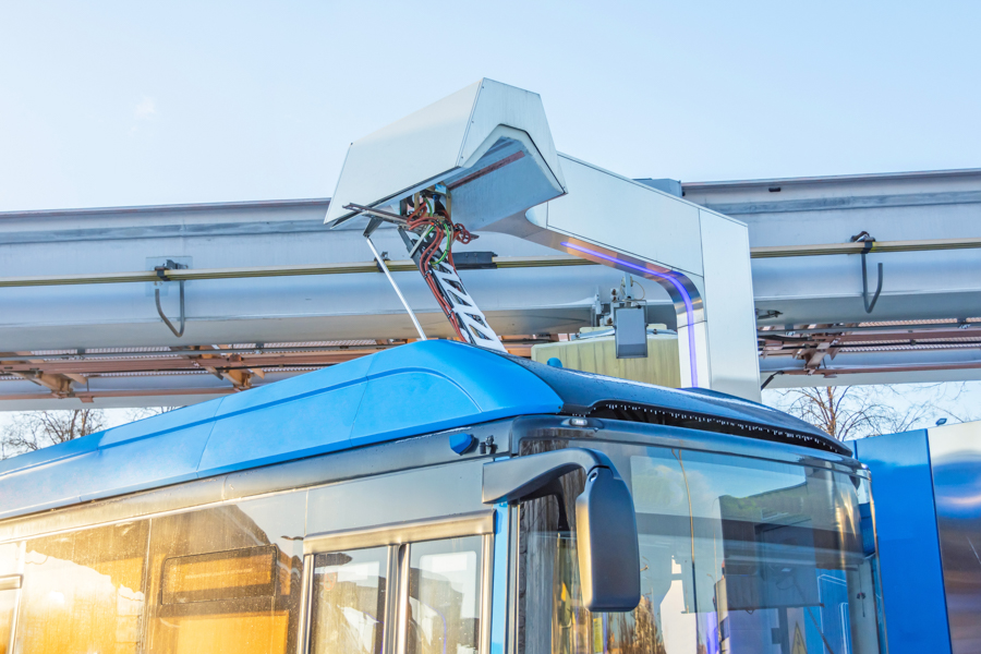A transit bus at a depot using an overhead charger.