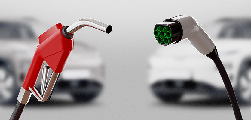 A “gas versus electric vehicle” concept photo showing a gas nozzle next to an electric vehicle plug, with their respective vehicle types in the background. 