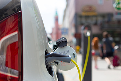 An electric vehicle recharges at a curbside public charger situated near shops and restaurants.