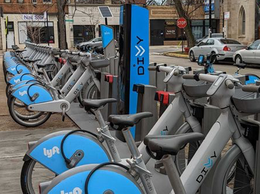 A rack of electric bikes and a charging station in proximity to a busy city street.