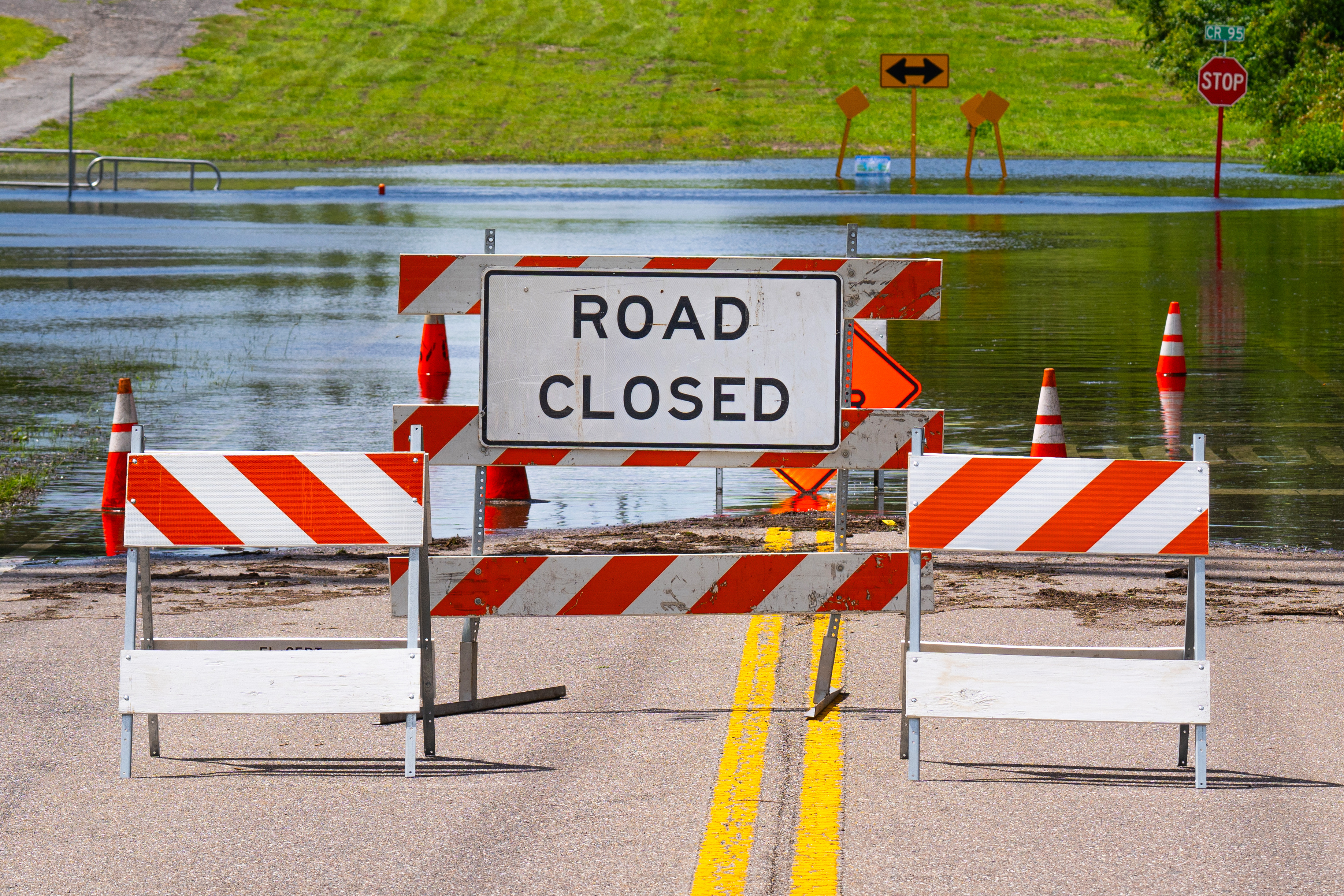 Road closed sign in front of a flooded roadway (Adobe Stock).