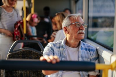 Older man sitting on bus looking out the window.