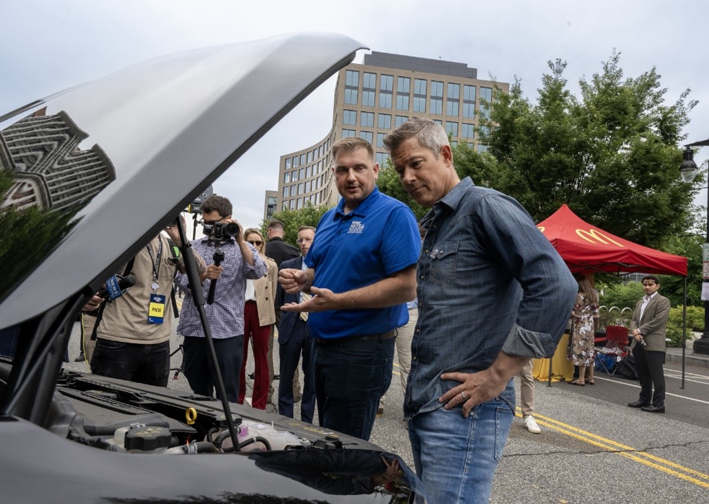 Secretary Duffy with mechanic looking at the engine of a car