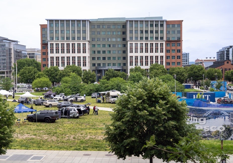 The Great American Road Trip line of vehicles with USDOT HQ building in background