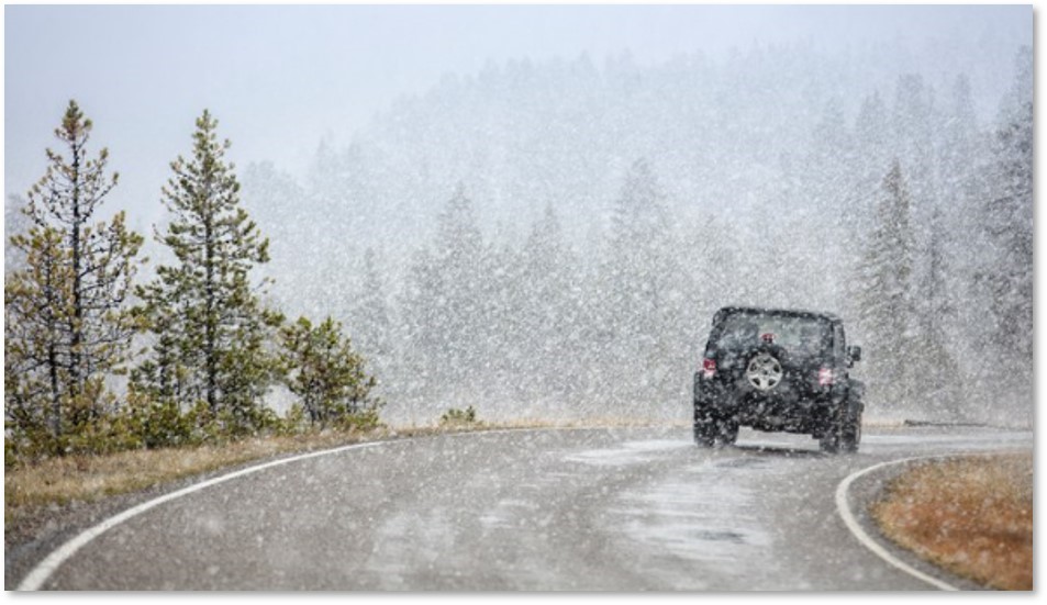Jeep traveling down a road in snowy weather