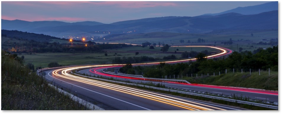 Curved road with headlight and taillight trails