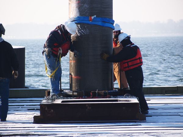 Photo of workers driving the first pile into the seabed of the rebuilt Mallory Pier