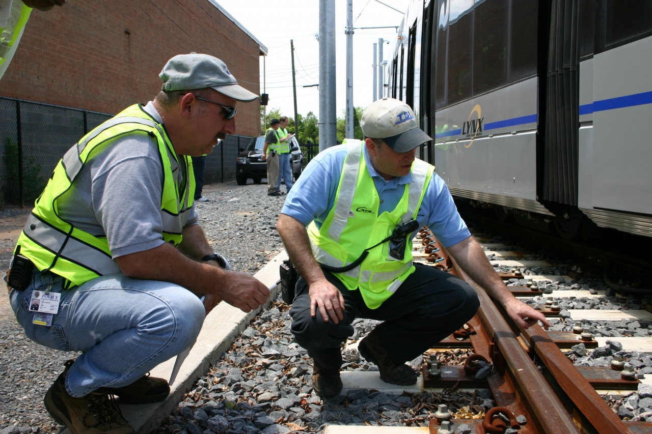 Photo of two TSI employees squatting and inspecting a train and rail