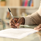 A person fills out an application form with a pen and paper.