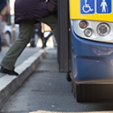 A pedestrian steps onto a bus from the curb.