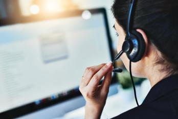 Person holding a headset in front of a computer screen