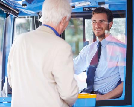 A smiling bus driver speaks to a patron.