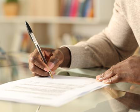 A person fills out an application form with a pen and paper.