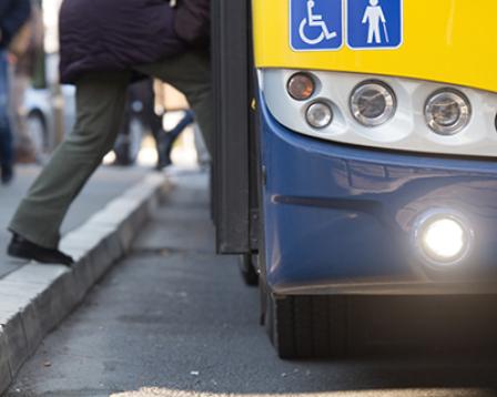 A pedestrian steps onto a bus from the curb.
