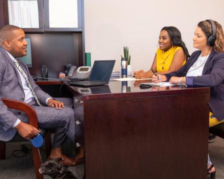 three people sitting around desk