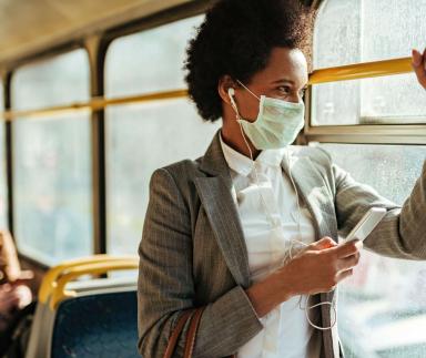 A woman wears a mask while riding a bus.
