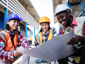 Group of three people in hard hats and safety vests looking at a schematic